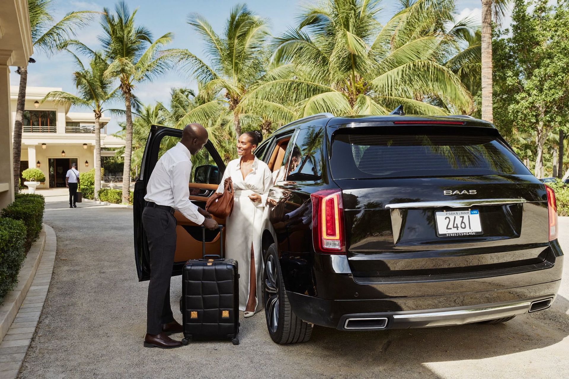 A chauffeur greeting guests beside a black luxury SUV at a Nassau resort