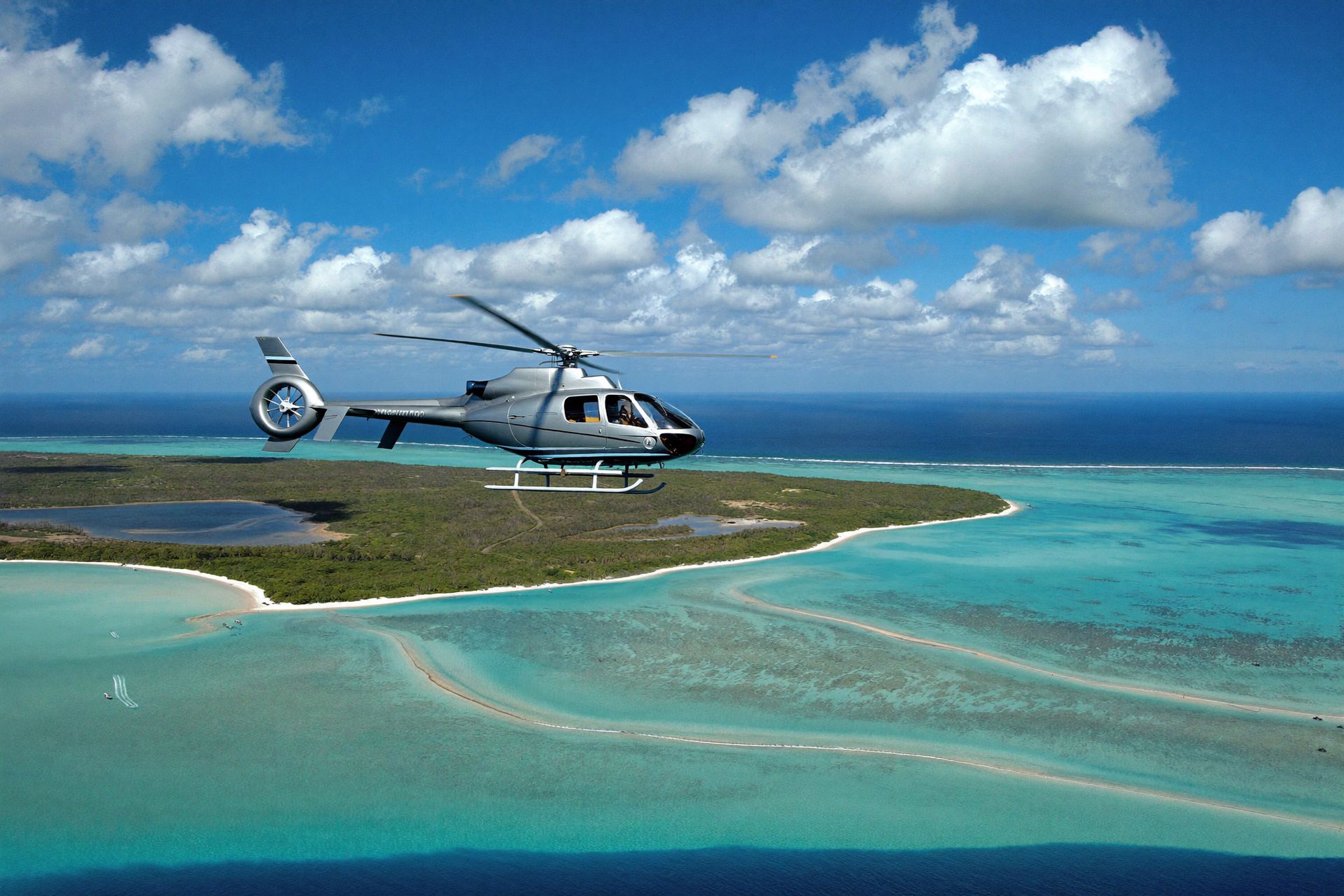 A private helicopter flying over the shallows of the Exuma Cays