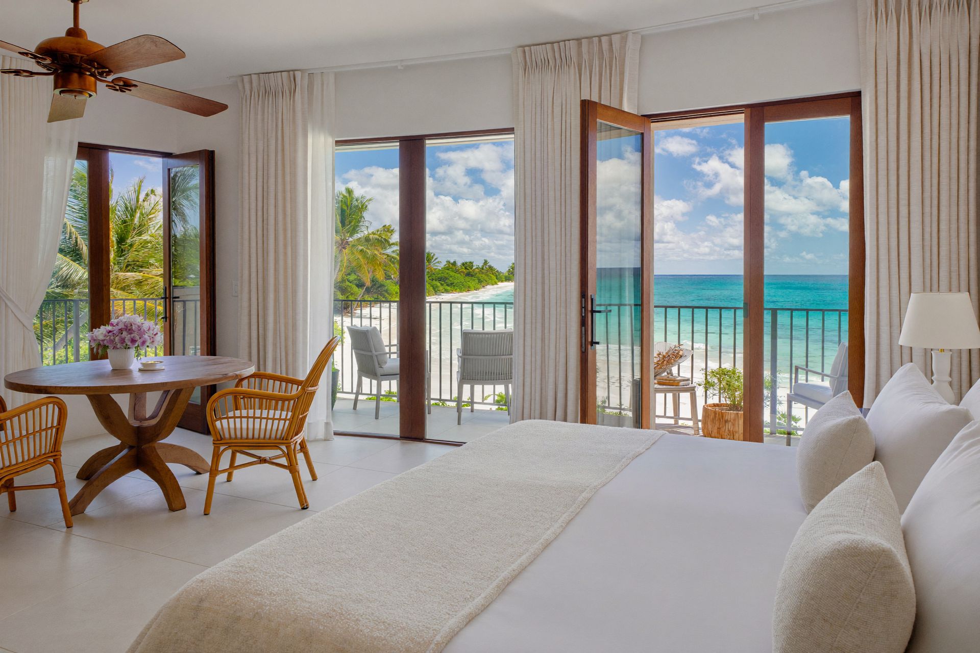 A bright beachfront suite opening onto a balcony over the sea