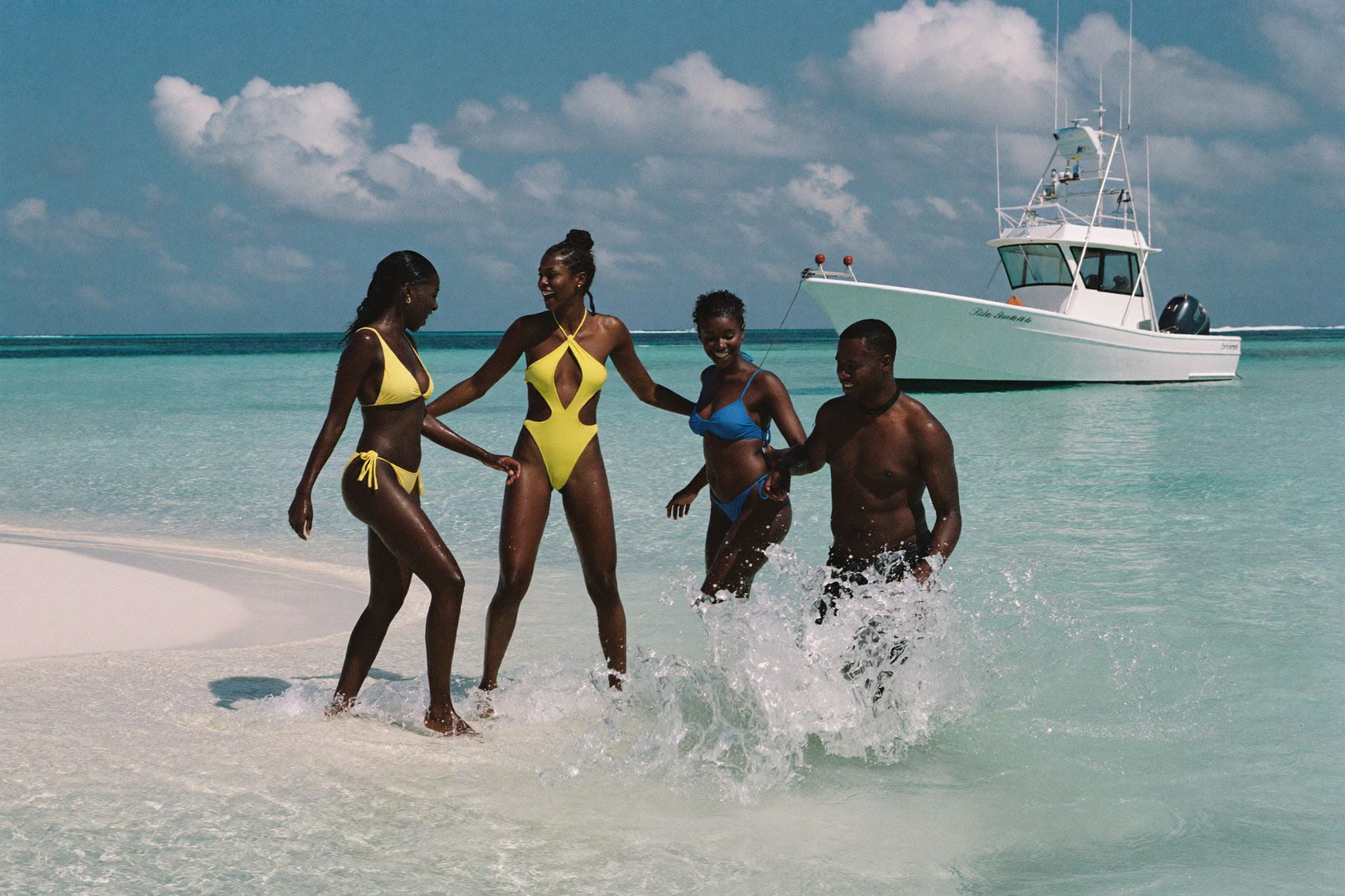 Friends laughing together on a sandbar in clear turquoise water