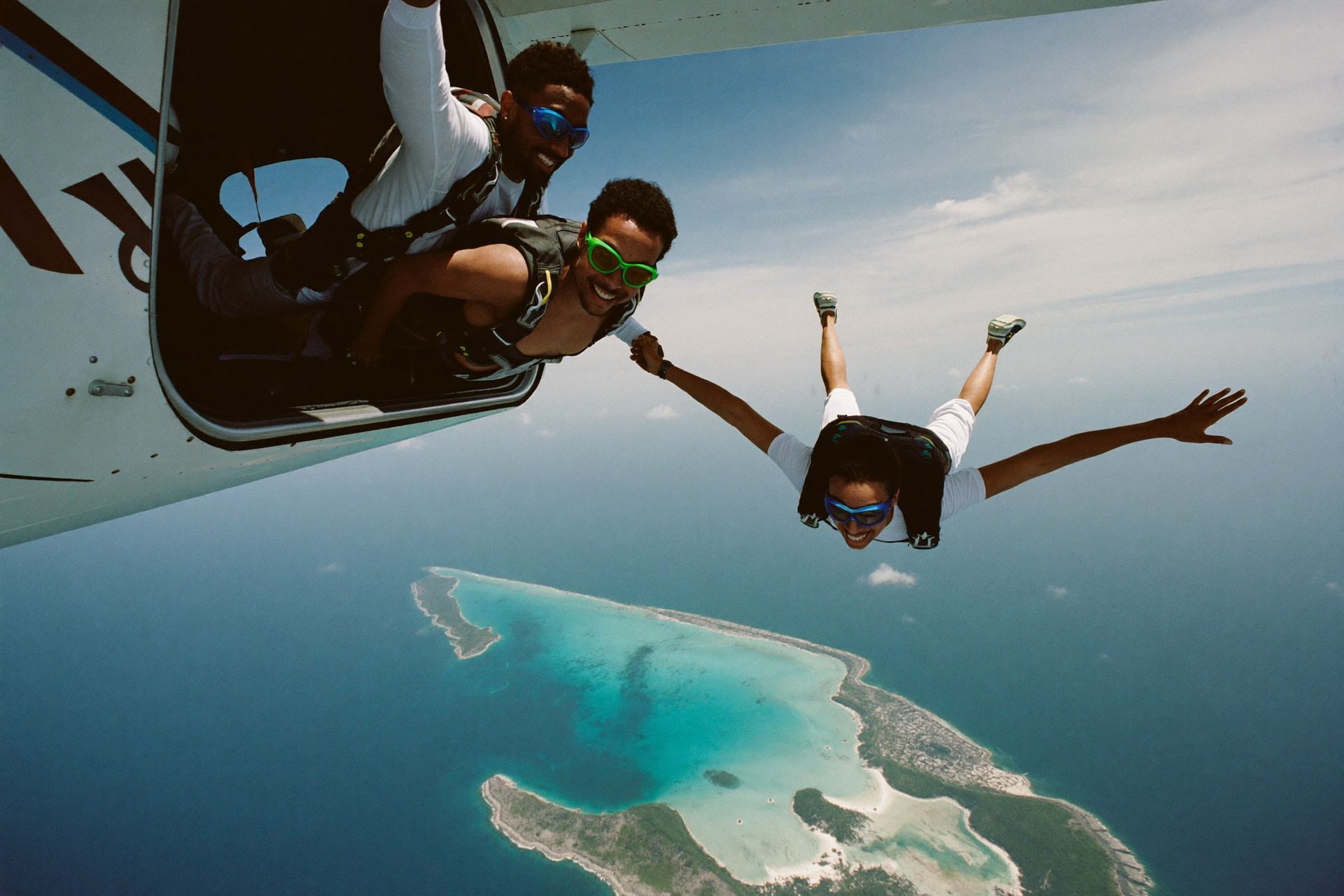 Skydivers leaving the jump plane high above the turquoise cays