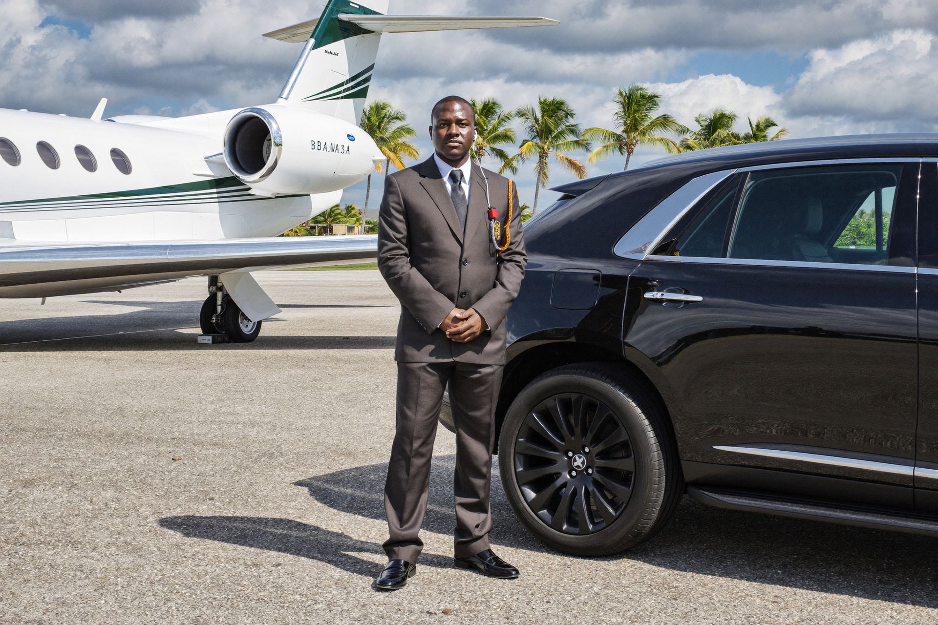 A close-protection officer beside a black SUV and a private jet